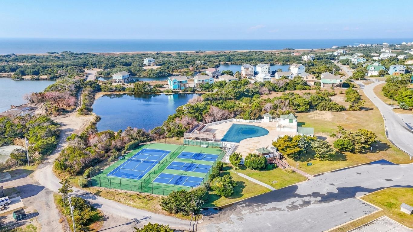 Aerial view of a lakeside community with tennis courts and a pool